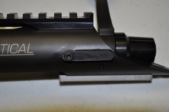 Close-up view of a Kelbly's Extreme Duty Bolt Stop installed on an Atlas Tactical rifle action. The bolt stop, visible along the side of the matte black receiver, enhances the rifle's functionality and safety. It's designed to withstand heavy use, ensuring reliable operation under various shooting conditions. The receiver also features a tactical rail and other precision-engineered details.