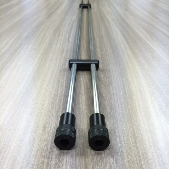 Image of Benchrite Double Cleaning Rod Case, featuring two parallel metal cleaning rods encased in black rubber grips, extending from a central T-bar handle, laid on a textured wooden surface. This case is designed for safely transporting and protecting precision cleaning rods for firearms.
