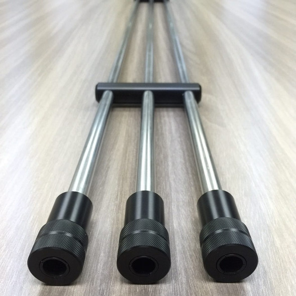 Close-up image of the Benchrite Triple Cleaning Rod Case featuring three metal cleaning rods with black rubberized grips, aligned parallel with a central black T-bar handle on a smooth wooden surface. Designed to protect and organize cleaning rods efficiently for firearm maintenance.