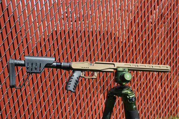 The image showcases the XLR Industries Element 4.0 MG Chassis for the Remington 700 Short Action, depicted in a robust Burnt Bronze finish that exudes a blend of tactical aesthetics and field-ready functionality. The chassis is outfitted with a Smoke Carbon Buttstock and a Carbon Fiber Ultralight Grip, which collectively contribute to its ergonomic design and lightweight profile without sacrificing durability. The foldable nature of the buttstock offers added convenience for transportation and storage, making the rifle compact and easy to handle. Positioned against a contrasting diamond-patterned backdrop, the chassis stands out as a high-performance foundation for precision shooting, catering to those who prioritize customization, ergonomics, and advanced engineering in their shooting equipment.