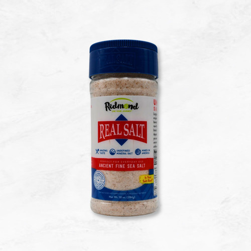 A sleek 10 oz. Redmond Real Salt shaker with a natural label, filled with fine grain, unrefined sea salt.