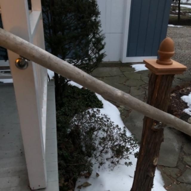 Wood acorn post cap on a 4x4 post beside a stair rail