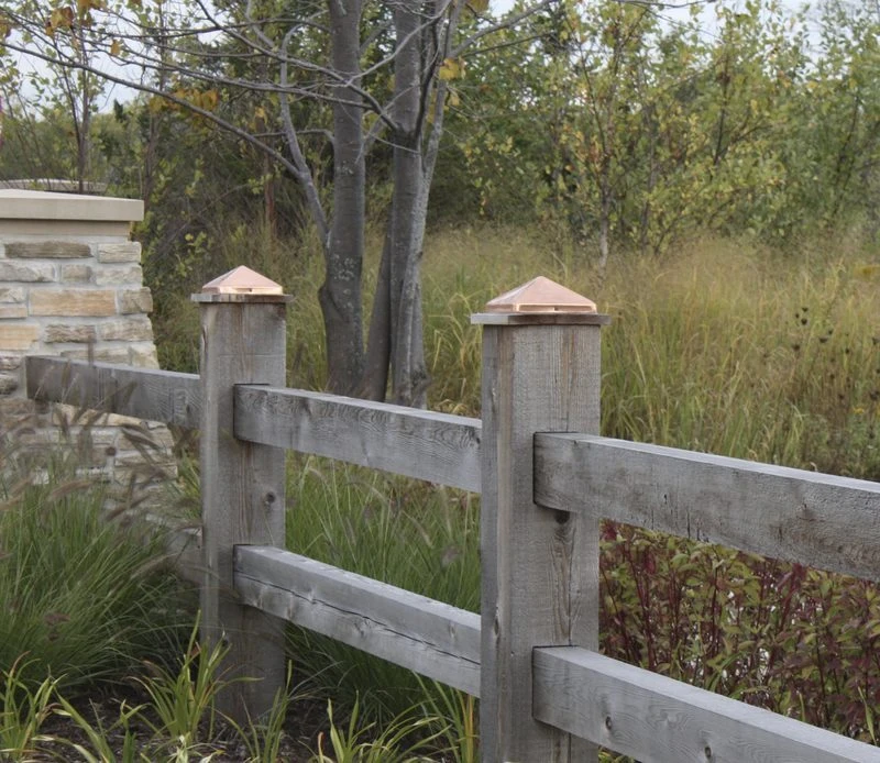 Bronze copper pyramid post caps on a split rail fence