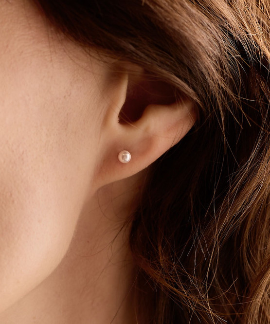 Up close image of Model wearing Hypoallergenic 4mm Natural Titanium Light Rose Pearl earrings