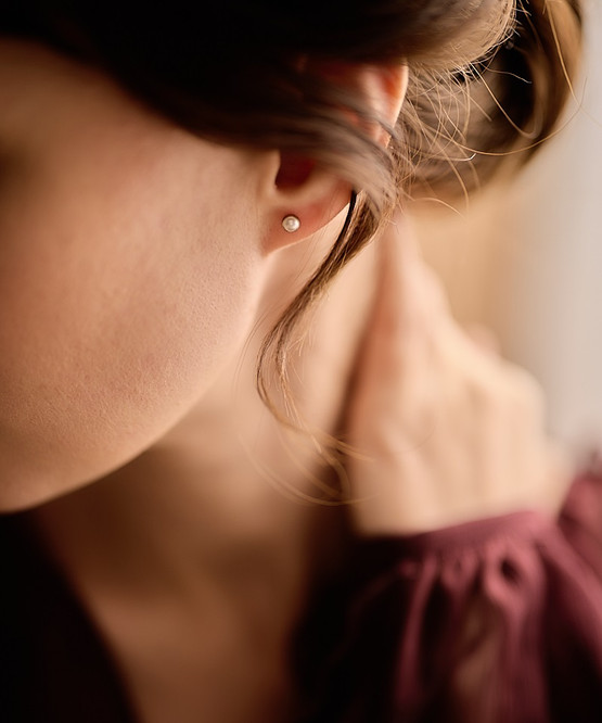 Model wearing the Hypoallergenic Golden Titanium 5mm Bezel White Pearl Earrings