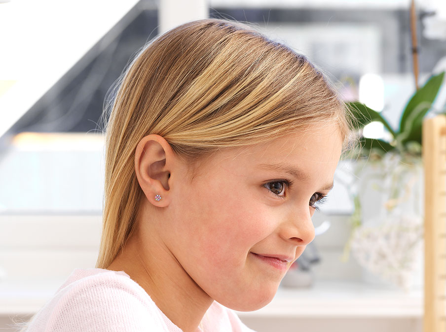 Cropped photo of a cute baby in mummy arms choosing golden small medical  earrings for ear piercing. White background Stock Photo - Alamy