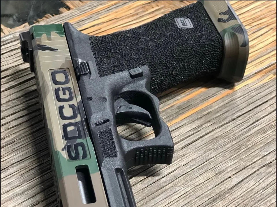 Close-up of the Glock 34's hand-stippled grip and frame, with the SDCGO slide plate in the foreground
