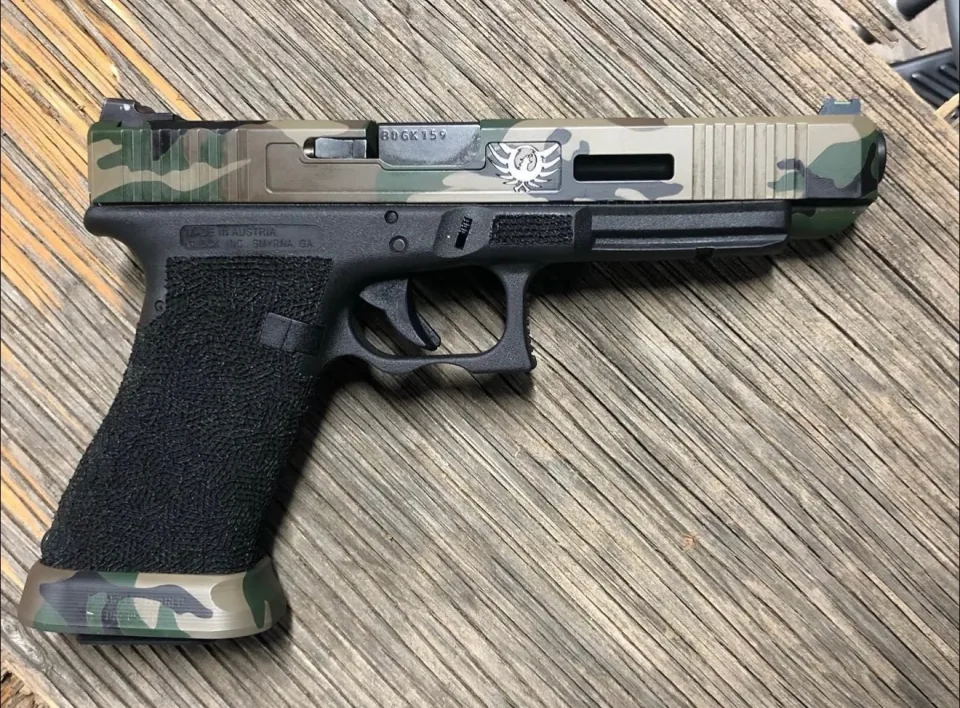 The other side of the same Glock 34: the camouflage slide with its markings and an eagle mark, the stippled grip and a camouflage magazine base plate
