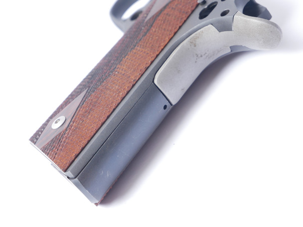Close detail view of EGW 1911 flat mainspring housing installed in pistol frame highlighting precision machined steel fitment alignment with grip safety junction and seamless integration into 1911 frame for upgraded durability and performance