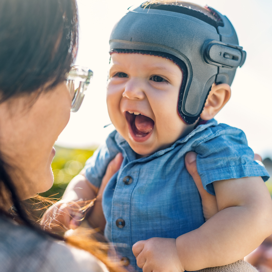 Close-up of a smiling baby wearing a grey MyCRO band being held by his mother. 