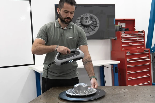 Reverse engineering specialist from an engineering team using an HP DesignScan 3D scanner to capture a physical part, creating accurate 3D data for reverse engineering, CAD modeling, and product development workflows.