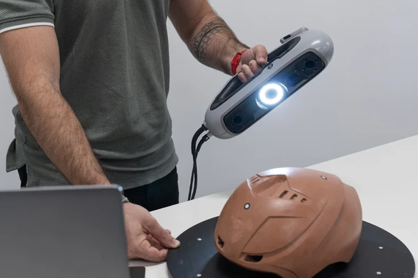 Portable HP DesignScan 3D scanner capturing the geometry of a plastic part to create an accurate digital model for CAD design and integration into 3D printing workflows.