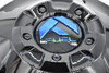 Close-up of gloss black Fuel Offroad wheel center cap with blue logo, part 1003-88GBK