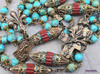 Vintage bronze Catholic rosary with turquoise and red coral beads, featuring Joan of Arc, St Michael, and St George medallions, adorned with fleur-de-lis symbols and the Cross of Lorraine for prayer and devotion.