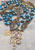 Unique antique-style heirloom rosary with blue mystic agate and peridot beads, featuring solid bronze medals of Our Lady of Guadalupe, Sacred Heart of Jesus, Our Lady of the Rosary, and sun and moon symbols for Catholic devotion.