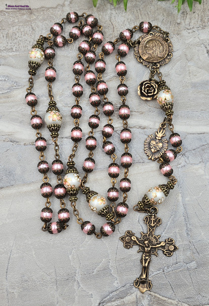 Unique antique-style rosary with pink imitation pearl glass beads and floral Japanese Tensha beads, featuring solid bronze medals of Mary Magdalene and the Sacred Heart of Jesus for Catholic prayer and devotion.