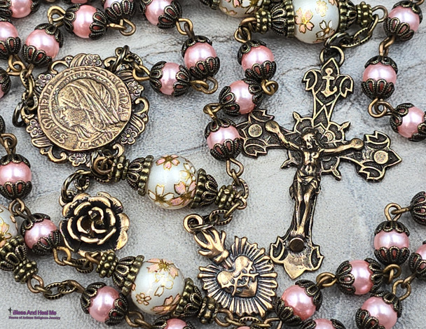 Unique antique-style rosary with pink imitation pearl glass beads and floral Japanese Tensha beads, featuring solid bronze medals of Mary Magdalene and the Sacred Heart of Jesus for Catholic prayer and devotion.