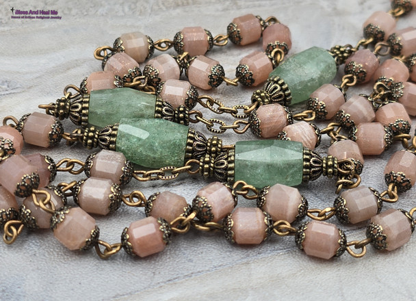 Unique antique-style heirloom rosary featuring solid bronze medals of a radiant Fatima center, sun medal associated with miracles, and a symbolic Miraculous Mary with a snake under her feet, crafted with peach moonstone and green strawberry quartz beads for Catholic devotion and prayer.