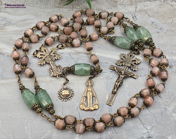 Unique antique-style heirloom rosary featuring solid bronze medals of a radiant Fatima center, sun medal associated with miracles, and a symbolic Miraculous Mary with a snake under her feet, crafted with peach moonstone and green strawberry quartz beads for Catholic devotion and prayer.