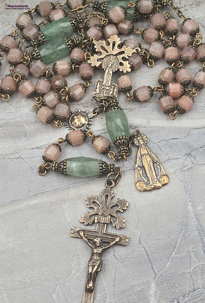 Unique antique-style heirloom rosary featuring solid bronze medals of a radiant Fatima center, sun medal associated with miracles, and a symbolic Miraculous Mary with a snake under her feet, crafted with peach moonstone and green strawberry quartz beads for Catholic devotion and prayer.