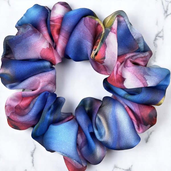 Tuhil Threads Large Vibrant Abstract Silky Satin Scrunchie. Luxurious large silky satin hair tie with a stunning abstract watercolor blend of rich blues, pinks, and purples for an eye-catching, gentle hold. Shop Tuhil Threads hair accessories.