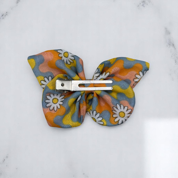 A vibrant Vibrant Retro Daisy Wave Print Small Polycotton Butterfly Bow by Tuhil Threads, measuring approximately 10cm wide by 6cm high. Shop Tuhil Threads hair accessories.