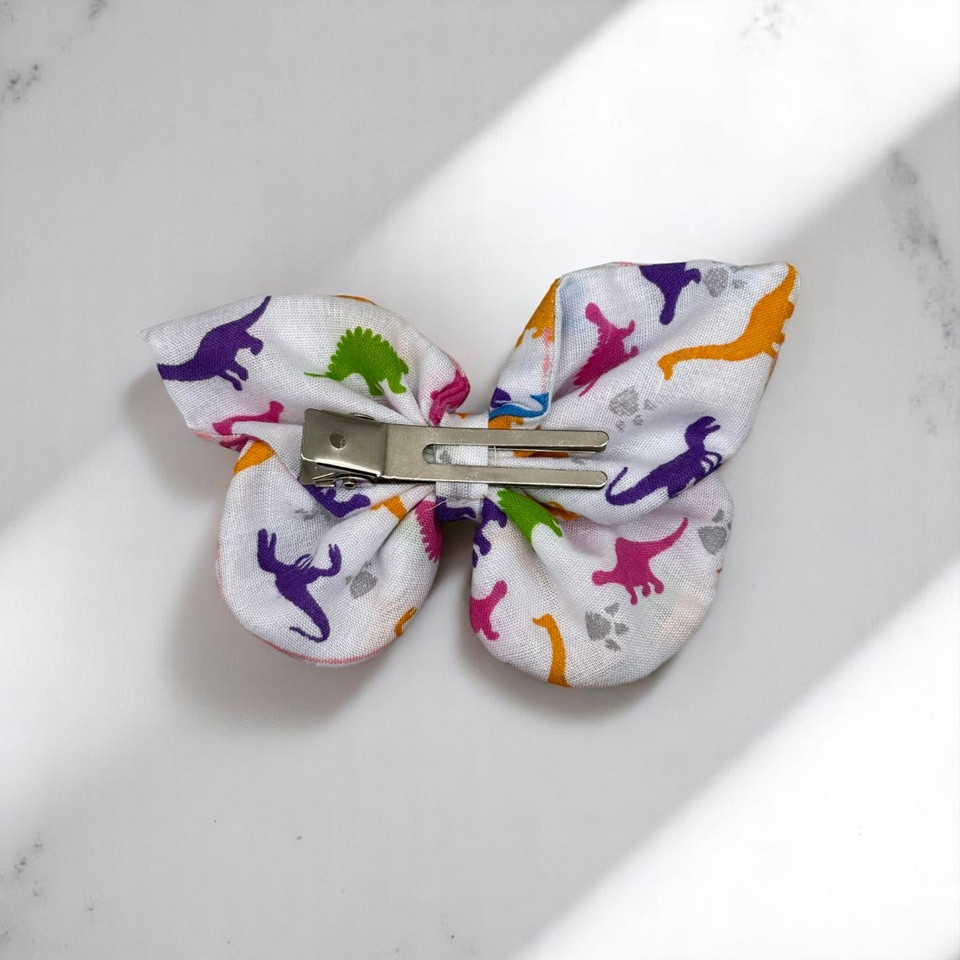 An adorable Dinosaur Print Small Polycotton Butterfly Bow by Tuhil Threads, measuring approximately 10cm wide by 6cm high. Shop Tuhil Threads hair accessories.