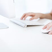 Close up of a user with one hand on the keyboard and one hand on a mouse