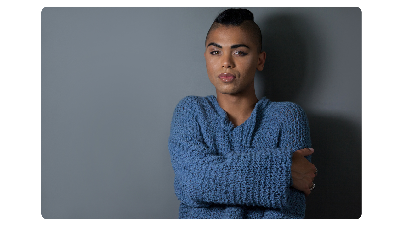 Confident transgender individual in a blue sweater expressing authentic self Gender X Life.com