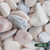 Close up photograph of Flamingo Pebbles. When dry stones are soft pink and cream tones with subtle speckling and a naturally rounded, smooth texture.