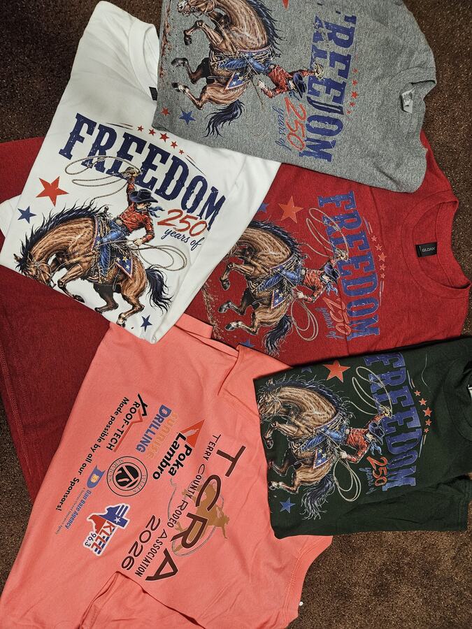 White, gray, red and dark shirts with detailed multicolor cowboy graphics, alongside a coral sponsor shirt.
