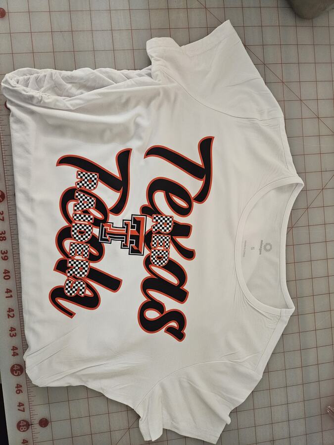 White Texas Tech Red Raiders shirt with black script, red outlines and checkerboard lettering.