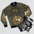 A bomber jacket featuring a captive unicorn amidst a lush green floral motif, inspired by fantasy and mythological elements. - Flat lay