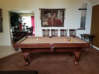 Classic wooden pool table with brown felt and pool balls in a home game room.