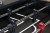 Close-up of foosball table rods with black and red players on a marked playing field.