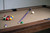 Brown felt pool table with cue stick and racked billiard balls ready for play.
