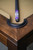 Corner detail of wooden pool table with leather pocket and cue stick resting.