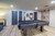 Canada Billiard Invitation pool table with grey wood finish, black basket pockets and dark cloth in a recreation room.