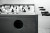 Stainless steel foosball table with black handles and circular ball return opening, close-up view.