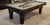 Black wooden pool table with gray felt and pool cues placed across the surface.