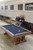 Man and woman leaning against a train with the Olhausen Railyard pool table in the forefront.