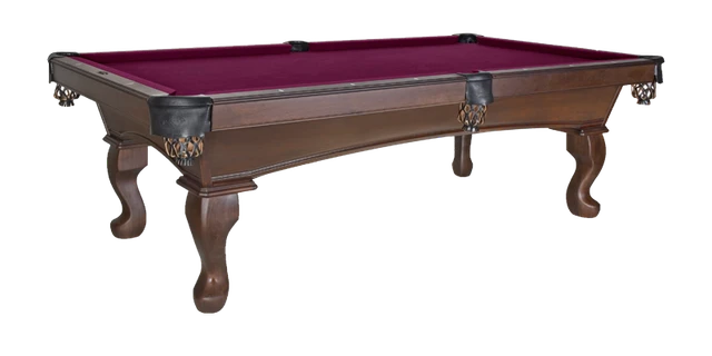 Elegant wooden pool table with red felt and ornate carved legs.