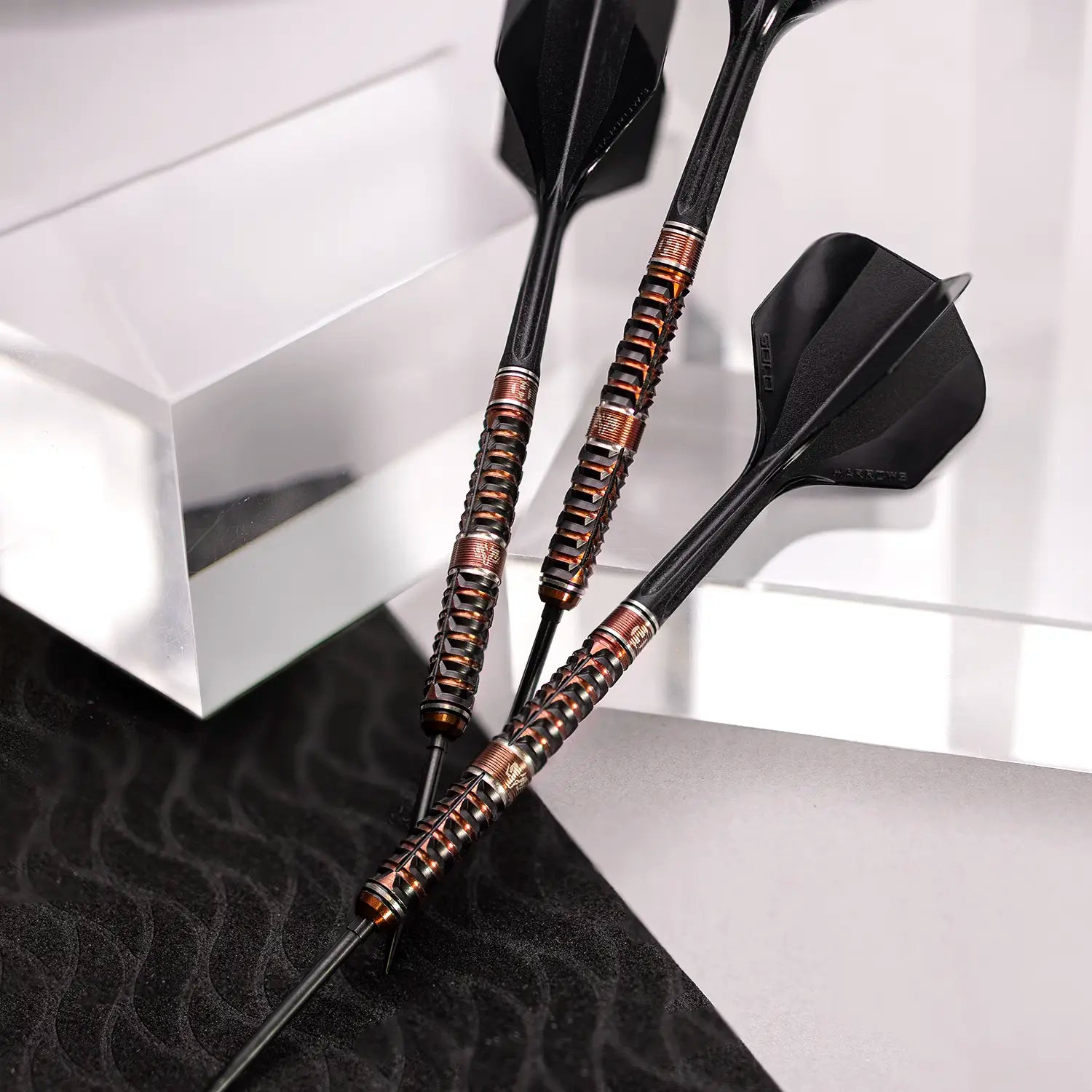 Two darts with black and copper design on a white and black checkered background