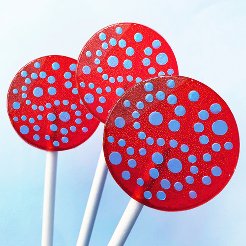 Three deep bright red lollipops on long white paper sticks are arranged against a light blue background in a fan layout. The lollipops each have a light blue pattern of dots.