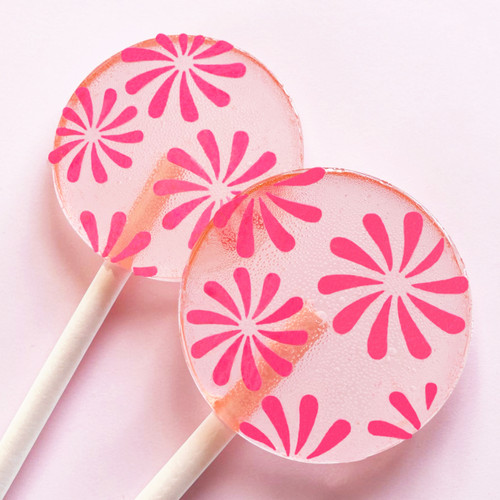 Two light pink, round, glossy hard candy Lollipops with extra long white paper lollipop sticks and pink color pinwheel flowers, on a light pink background.