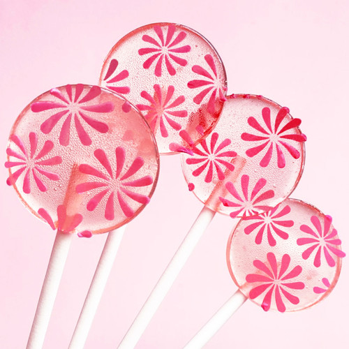 Four light pink, smooth, round, glossy Strawberry Banana hard candy Lollipops with extra long white paper lollipop sticks and coral pink color pinwheel flavor flowers, on a light pink background showing very pink-on-pink flower bunch bouquet.