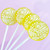 Four smooth, round, glossy bright yellow hard candy lollipops on top of extra long white paper lollipop sticks with white flower petal designs. All on a light purple background.