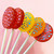 Five round lollipops on white sticks arranged in a fan shape. Two red lollipops feature light pink polka dots, while one yellow, one orange, and one red lollipop feature bright blue polka dots, all with a translucent, glossy finish.