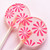 Two light pink, round, glossy hard candy Lollipops with extra long white paper lollipop sticks and pink color pinwheel flowers, on a light pink background.