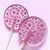 Two light purple, round, smooth, glossy hard candy Berries and Cream Lollipops with extra long white paper lollipop sticks, each with pink/purple spiral confetti flavor dots on a light purple/pink background.